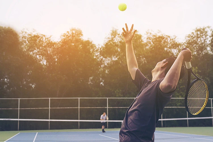 2 men playing tennis at an outdoor court